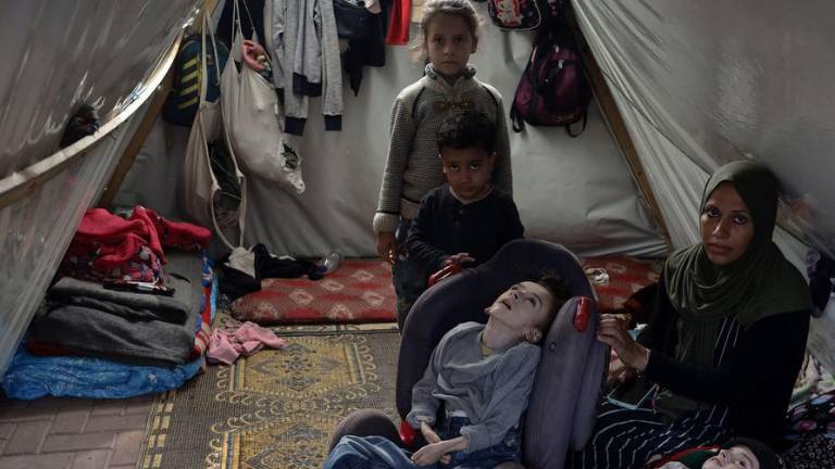 Mena, madre desplazada de cuatro hijos, con sus cuatro hijos en una tienda de campaña dentro de la Universidad Abierta Al-Quds, en la Franja de Gaza.