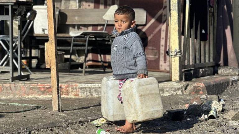 Un niño transporta bidones de agua en la Franja de Gaza.