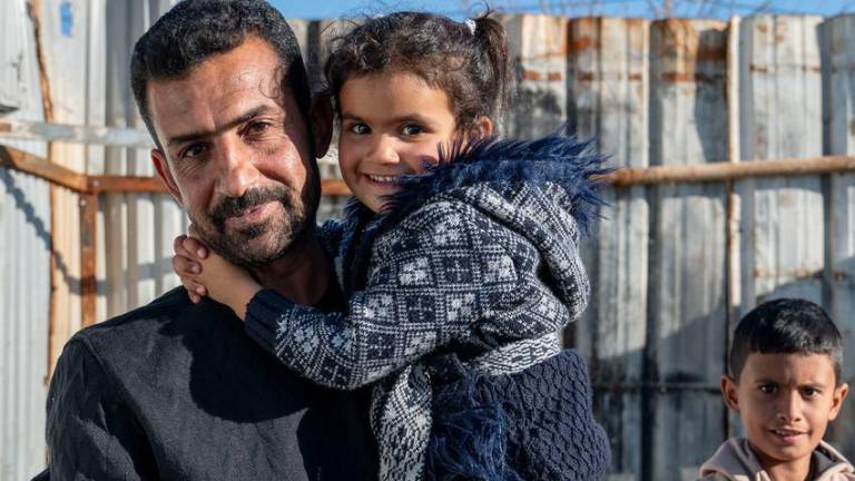 Un refugiado sirio, padre de seis hijos, sostiene en brazos a su hija de cinco años. Vive con su familia en el campo jordano de Azraq desde 2016.