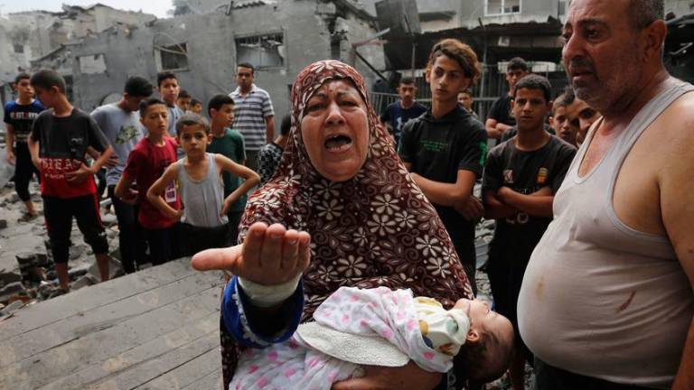 Familias palestinas frente a edificios dañados y destruidos por los bombardeos israelíes a Gaza.