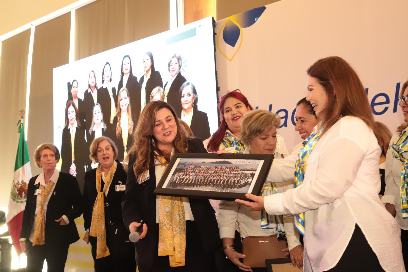 $!Elizabeth Peraza, directora ejecutiva del Grupo Datemex y coordinadora general del evento, hace entrega de la foto oficial de la Junta Nacional de Anspac Mazatlán 2025, a Martha González Pérez, presidenta del Comité Nacional.
