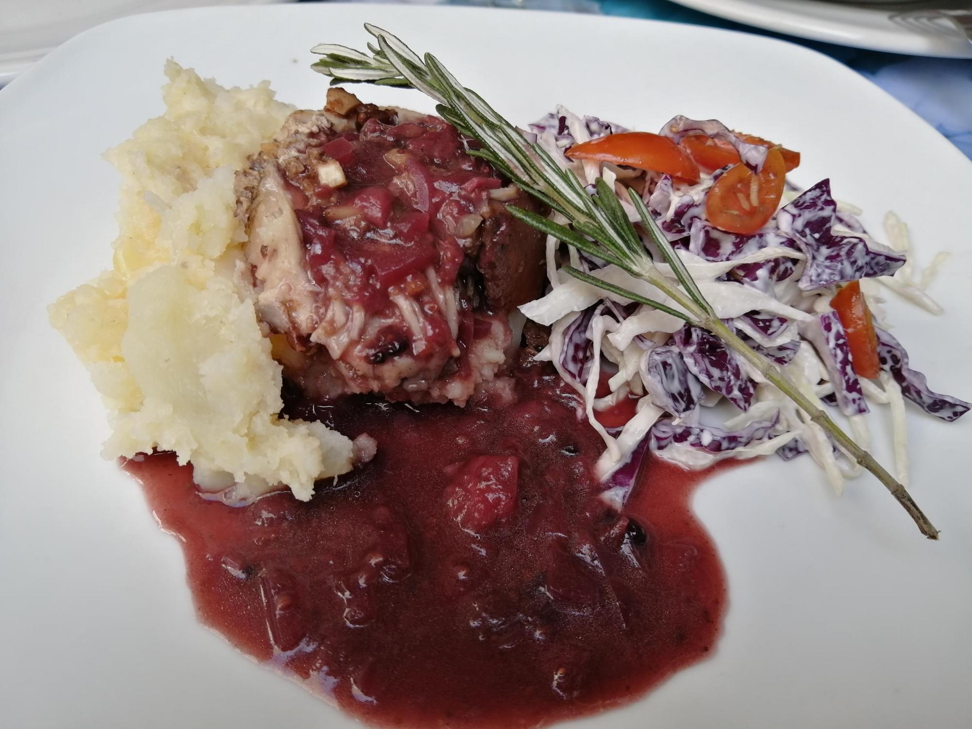 $!Pierna de puerco en salsa de arándanos y puré de papa, con ensalada de col morada.