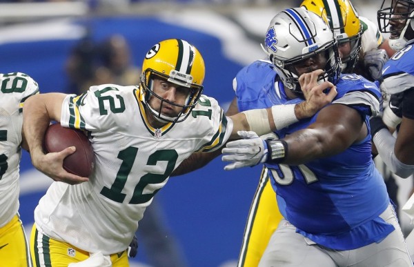 Aaron Rodgers (12) intenta evitar la tacleada de A'Shawn Robinson (91).