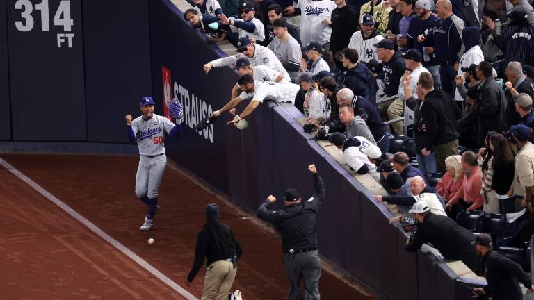 Mookie Betts reclama al umpire que dos aficionados trataron de arrebatarle la pelota que había atrapado.