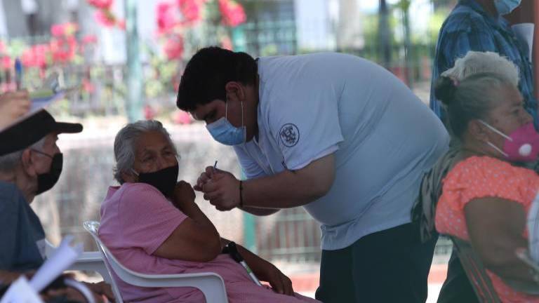 Una adulta mayor es vacunada por un enfermero.