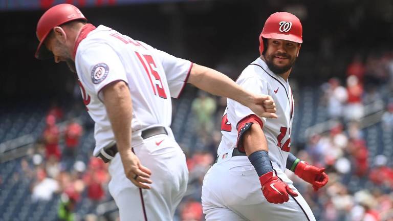 Kyle Schwarber celebra uno de sus dos jonrones con el coach de la antesala de los Nacionales.
