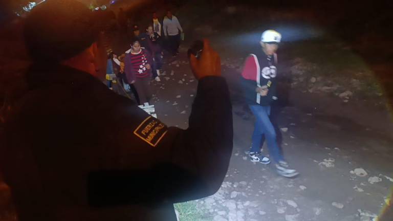 Un agente de la Policía Municipal de Escuinapa ayuda a iluminar a peregrinos que acuden a honrar a la Virgen de Guadalupe.