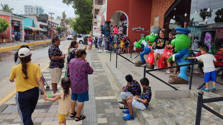 Visitantes visitan playas y comercios locales.