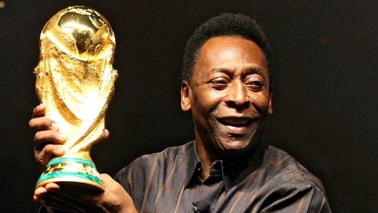 Pelé con uno de los tres trofeos de campeón de la Copa del Mundo que ganó su en trayectoria.