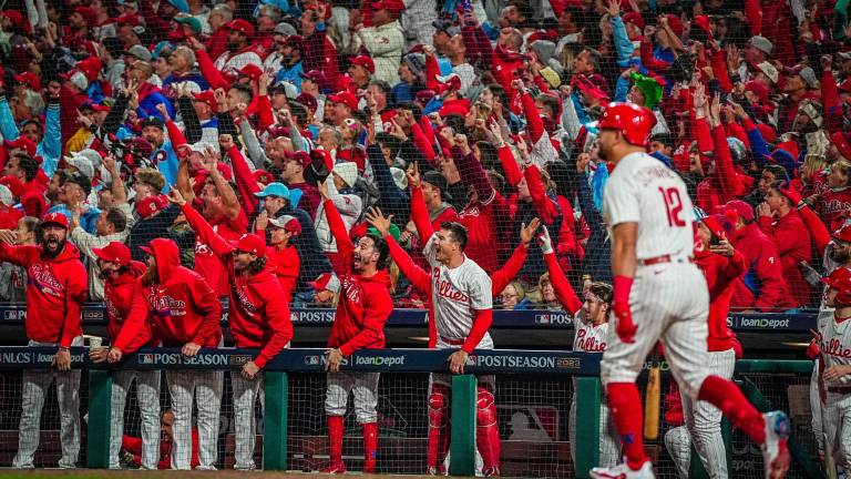 Kyle Schwarber observa su jonrón ante el festejo de sus compañeros y los aficionados de Filadelfia.