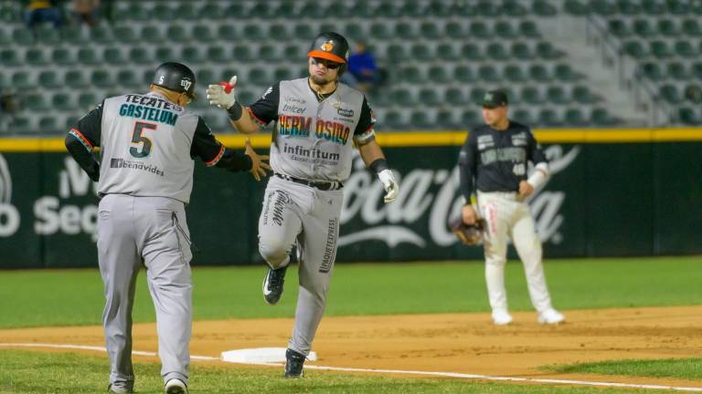 Andrés Sosa es felicitado por el coach de tercera base de Naranjeros tras su cuadrangular.