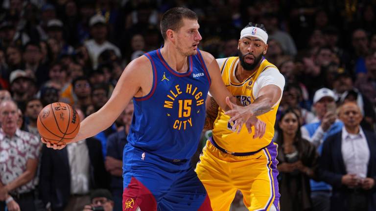 Nikola Jokic protege la posesión del balón ante Anthony Davis, en el primer juego de la temporada de la NBA.