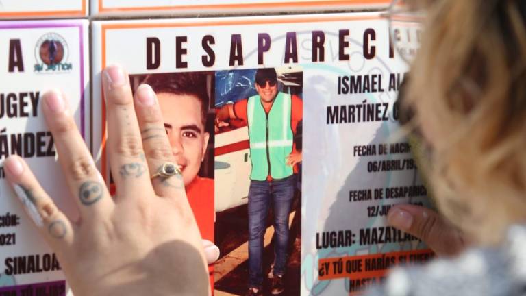 Una mujer presiona con fuerza el azulejo en el que está el rostro de uno de sus familiares desaparecido.