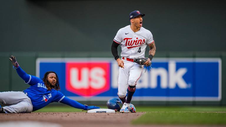 Vladimir Guerrero Jr. quedó postrado mientras Carlos Correa celebra la jugada.