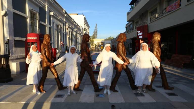 Un grupo de religiosas posa feliz frente al monumento a Los Beatles.