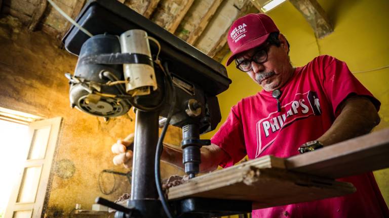 Evaristo trabaja bajo un techo de adobe y una luminosa ventana que dibuja los contornos polvorientos del taller.