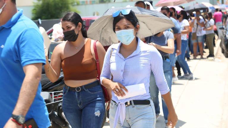 Sombrillas y gorras usan los jóvenes para esperar en las filas a vacunarse.