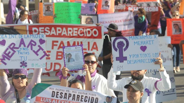 Mujeres marchan vestidas de morado, de negro y con pancartas en mano por el malecón de Mazatlán.