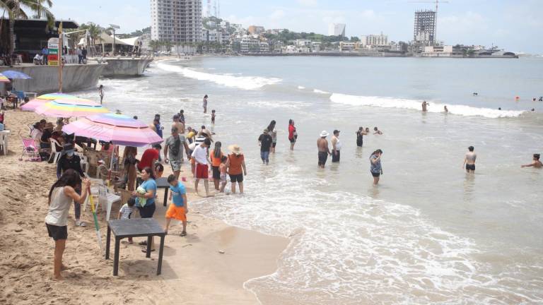 Los turistas disfrutan de un día familiar en las playas de Mazatlán.