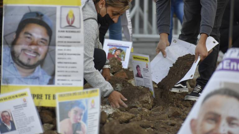 Frente a Palacio Nacional, en diciembre de 2021, integrantes de colectivos de búsqueda de personas desaparecidas simularon con montículos de tierra la existencia de una fosa clandestina, en la que colocaron imágenes de quienes permanecen ausentes.