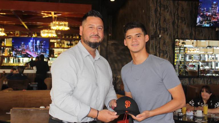 José Carlos Meza muestra la gorra de los Gigantes de San Francisco, equipo con el que recién acaba de firmar.