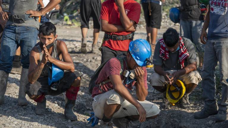Mineros dicen que andar bajo tierra “ingre”, la tierra les llama de generación en generación. En la imagen, tres trabajadores reaccionan ante la noticia del hallazgo sin vida de otro de sus compañeros.