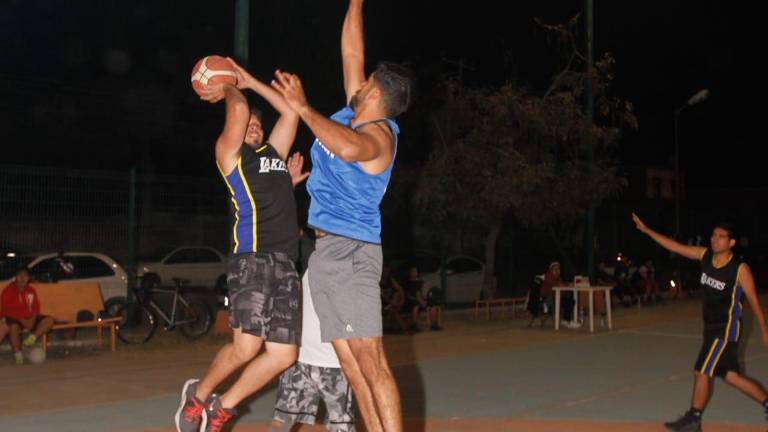 Martín Meza, de Cremería del Bajío, intenta bloquear el disparo de un rival, durante la actividad del Torneo de Baloncesto de Segunda Fuerza.