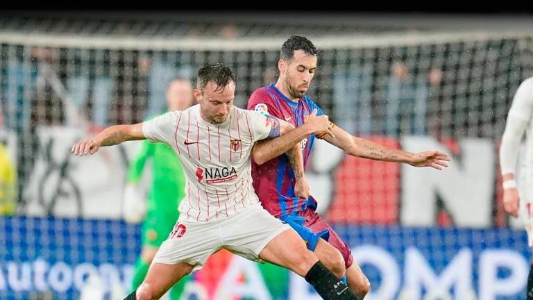Iván Rakitic disputa el esférico con Sergio Busquets, en el empate entre Sevilla y Barcelona.