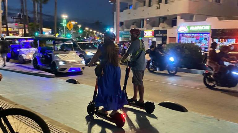 Turistas y locales recorren en scooters la ciclovía del malecón de Mazatlán cumpliendo con las medidas de seguridad establecidas por el Ayuntamiento.