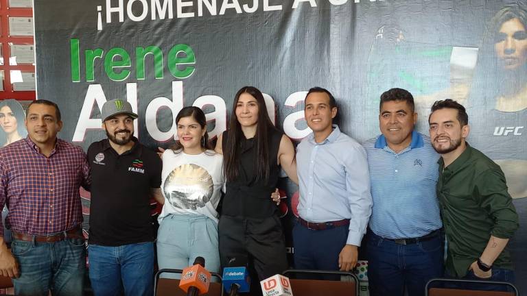 Irene Aldana (centro) es homenajeada por su trayectoria en las artes marciales mixtas.