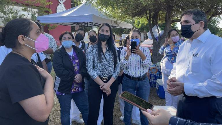 Héctor Melesio Cuén Ojeda, secretario de Salud estatal, dialoga con una trabajadora sanitaria.