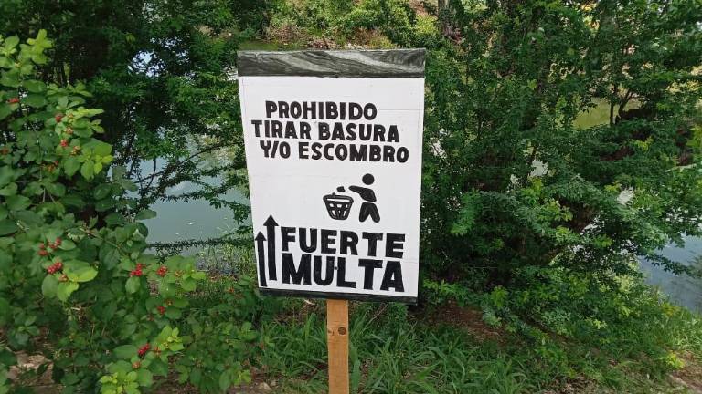Un anuncio advierte de sanciones a quienes tiren basura en los márgenes de la Laguna del Iguanero, en Rosario.