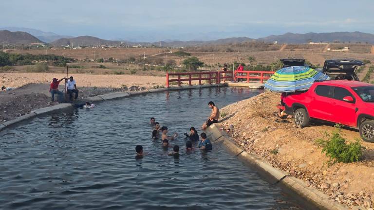Vecinos de La Estación encuentran refugio del calor en canales de la presa Santa María.