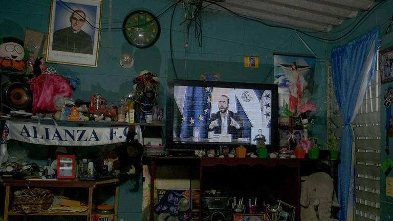 El presidente de El Salvador, Nayib Bukele, aparece en televisión en una casa en la colonia Mariona, un barrio de San Salvador controlado por la pandilla MS-13, mientras habla sobre la destitución del fiscal general y los jueces de la Corte Suprema, el 4 de mayo de 2021. El reemplazo de Los jueces de la Corte Suprema elegido por Bukele y el partido oficialista Nuevas Ideas le dieron el control efectivo de las tres ramas del gobierno. El control absoluto de todas las llaves del estado le ha permitido extender el régimen de excepción por un año. Hoy, el máximo comandante de la policía reporta directamente al Presidente y a la Corte Suprema que también es controlada por Bukele, donde ha creado “tribunales especializados” específicamente para revisar los arrestos derivados del régimen de excepción. A pesar de estos movimientos autoritarios, Bukele es uno de los líderes más populares de América Latina. En septiembre de 2022, anunció su intención de postularse para un segundo mandato, a pesar de que la Constitución salvadoreña prohíbe específicamente que los presidentes cumplan dos mandatos consecutivos.