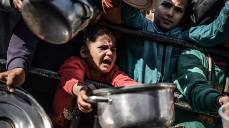 Shaima, de 8 años, espera su turno entre la multitud para recibir comida de un hospicio caritativo que distribuye alimentos gratuitos en la ciudad de Rafah, en el sur de la Franja de Gaza.