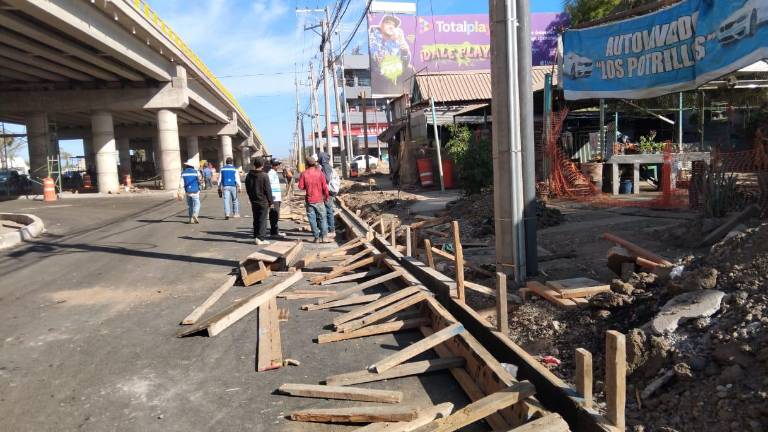 Los trabajadores laboran en la colocación del asfalto y reacomodo de banquetas en las laterales del puente del Libramiento Colosio.