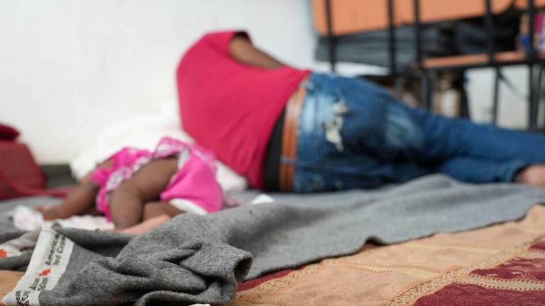 Una niña y un adulto duermen en un centro para personas desplazadas en Haití.