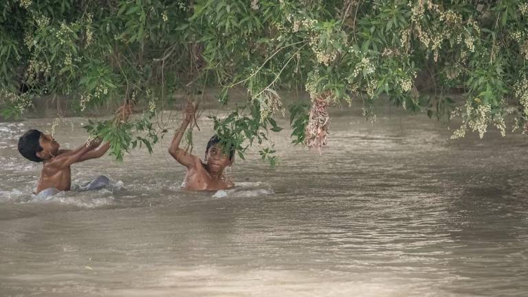 Niños vadean un canal inundado en Pakistán, donde las lluvias monzónicas de este año han dejado a muchas familias sin hogar, sin agua potable y sin escolarización (foto de archivo).