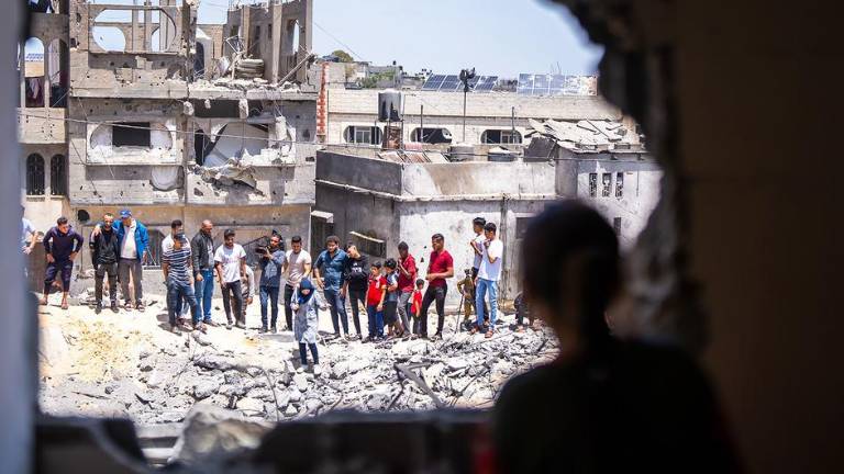 La gente observa los daños a las viviendas de un barrio en Gaza.