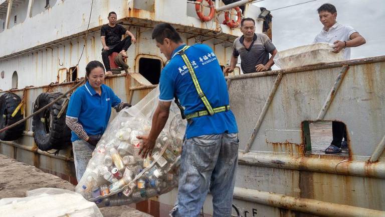 Trabajadores retiran residuos plásticos de un barco pesquero frente a la costa este de China.