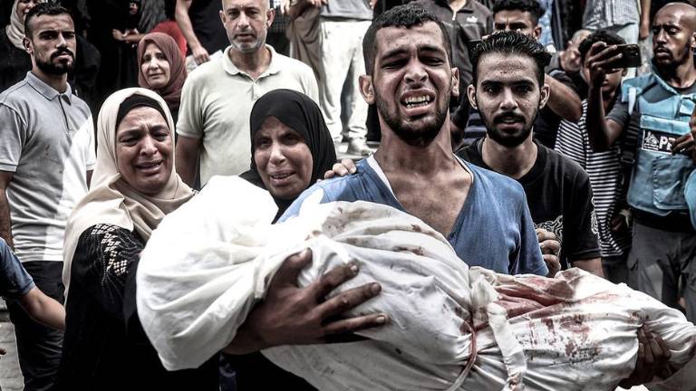 Un hombre lleva en brazos a una niña asesinada en un bombardeo israelí en Gaza.